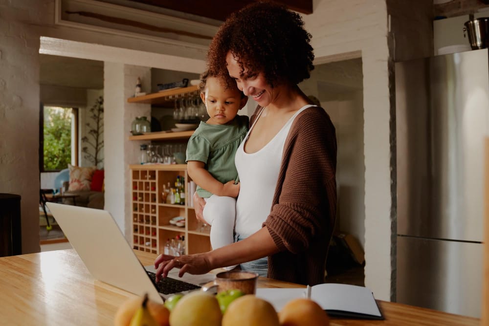 mother applying for snap benefits online while holding her child in the kitchen